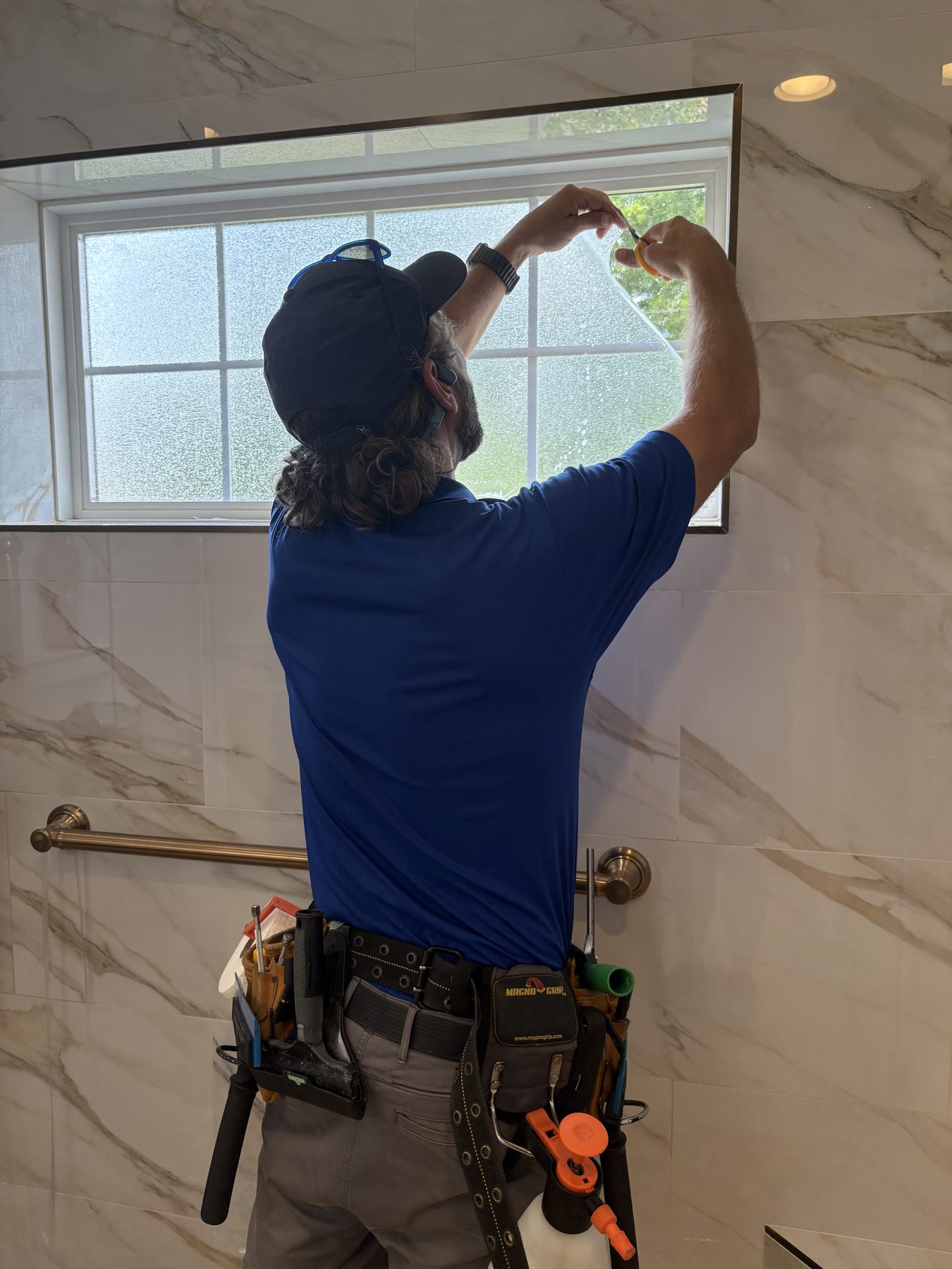 Frosted decorative film going onto a shower window in a marble bathroom