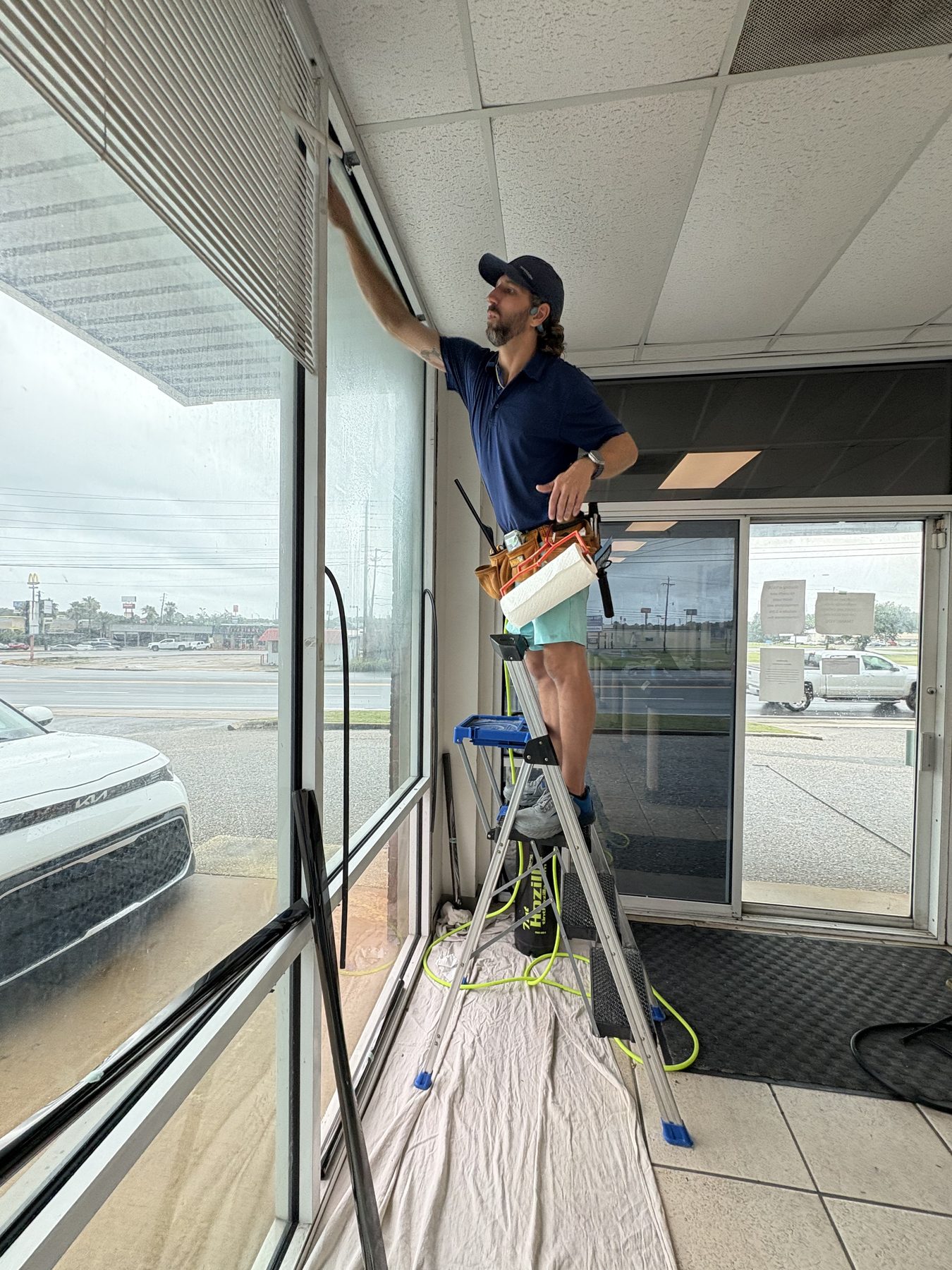 Cleaning storefront glass before an install, drop cloth down
