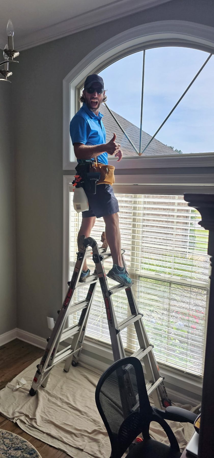 Joe installing window film on a tall arched window in a Mobile home