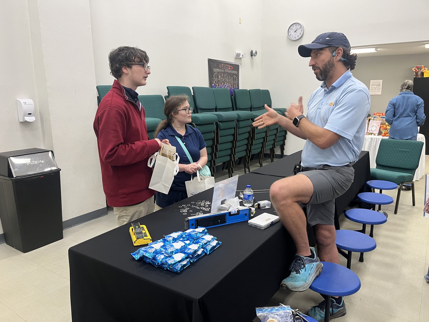 Explaining window film across a table of samples at a community event