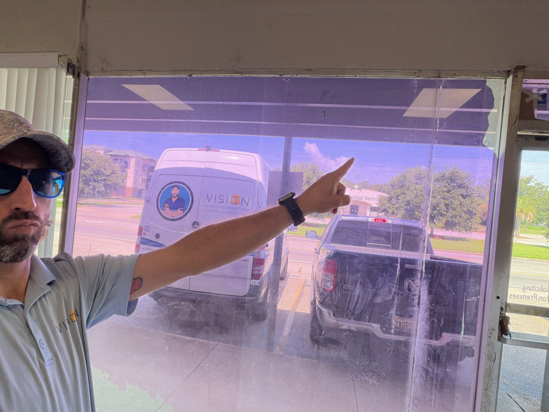 Joe pointing at failed window film that has turned purple on a storefront in Mobile